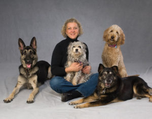 Janice posing with four dogs.