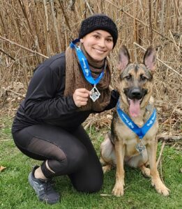 Natasha and dog wearing medals, posing.