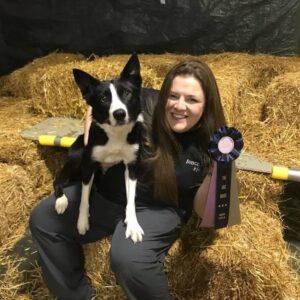 Bonnie holding prize ribbon and posing with dog.