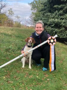 Hali showcasing prize ribbons with dog posing.
