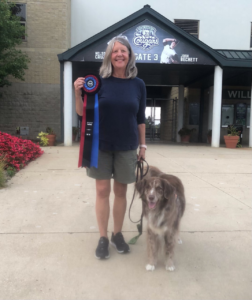 Karen holding prize ribbon with dog posing.